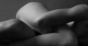 Frau liegt still und sanft umhüllt auf einer weichen Unterlage, der Körper entspannt, die Augen geschlossen – ein Moment tiefer Selbstverbindung und somatischer Beziehungsheilung.